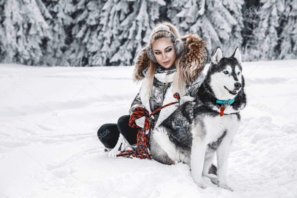 Happy young woman playing with siberian husky dogs in winter day.Attractive young woman with dog in wintertime outdoor. Amazing landscape.