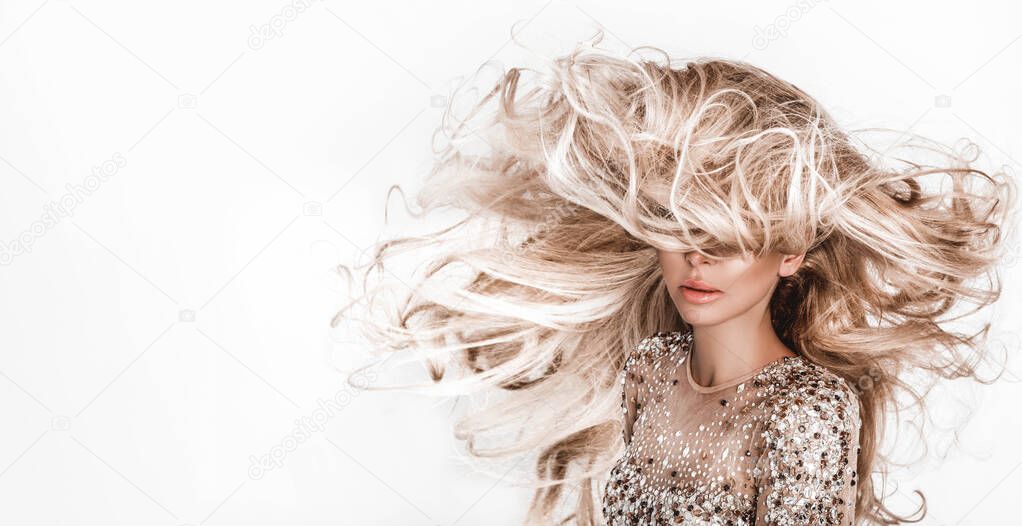 Blonde girl with long and shiny wavy hair . Beautiful model with curly hairstyle .