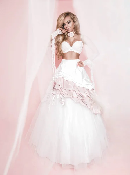 Mooi blond vrouw model in een bruiloft jurk op een roze backg — Stockfoto