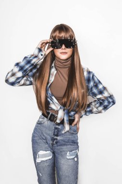 Pürüzsüz saçlı güzel bir genç kızın moda portresi. Bluzlu ve kot pantolonlu kız. Kıyafet ve saç stili. Güneş gözlüklü bir genç. Modaya uygun. Cazibeli stil düşkünü genç model