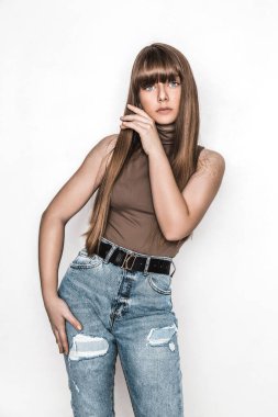 Pürüzsüz saçlı güzel bir genç kızın moda portresi. Bluzlu ve kot pantolonlu kız. Kıyafet ve saç stili. Modaya uygun. Okullu genç. Cazibeli stil düşkünü genç model