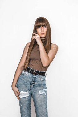 Pürüzsüz saçlı güzel bir genç kızın moda portresi. Bluzlu ve kot pantolonlu kız. Kıyafet ve saç stili. Modaya uygun. Okullu genç. Cazibeli stil düşkünü genç model