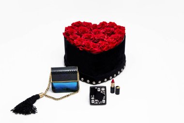 Zarif bir kutuda kırmızı güller kalp şeklinde ve beyaz arka planda parfüm. Lüks hediye konsepti. Sevgililer ve kadınlar günü hediyesi. Cazibeli çiçek kutusu.