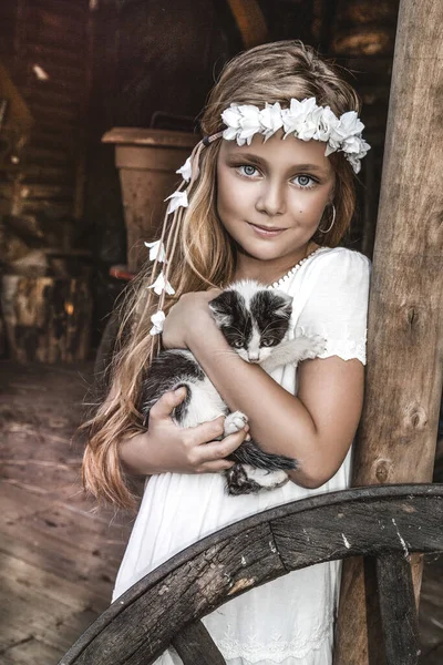 優しさと猫を愛し 幸せと笑顔の小さなかわいい子供の肖像画 子猫と公園でリラックスしている少女 白い聖餐式のドレスの子供は猫とキスしている 春のファッション — ストック写真