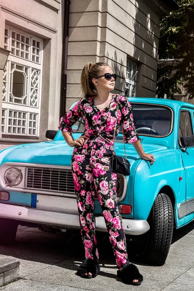 車の近くの花の服の美しい若い女の子 春と夏のティーンエイジャーのファッションモデルのコンセプト — ストック写真