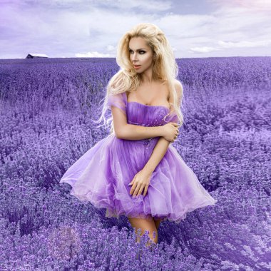 İlkbaharda ya da gündoğumunda lavanta tarlasında yürüyen güzel bir model. Lavanta tarlasında sarı saçlı kız - Görüntü