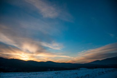 Kış mevsiminde gün batımında karlı dağların manzarası