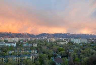Almaty, Kazakistan - Nisan 2020: Yeşil şehirde, dağların önünde altın kubbeli modern cami. Almaty 'de günbatımı. Pencereden en iyi görünüm.