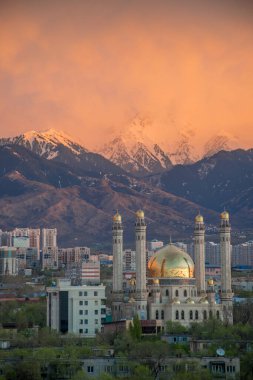 Almaty, Kazakistan - Nisan 2020: Yeşil şehirde, dağların önünde altın kubbeli modern cami. Almaty 'de günbatımı. Pencereden en iyi görünüm.