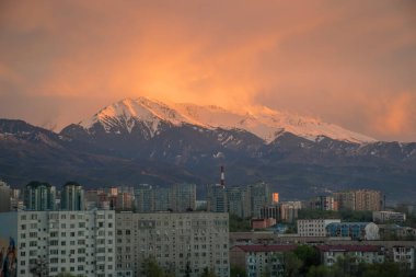 Almaty, Kazakistan - Mayıs 2018: Tian Shan dağı yakınlarındaki Almaty şehrinin üzerinde bulutlu bir gün batımı.