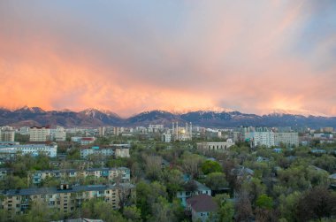 Almaty, Kazakistan - Nisan 2020: Yeşil şehirde, dağların önünde altın kubbeli modern cami. Almaty 'de günbatımı. Pencereden en iyi görünüm.