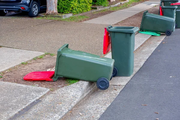 Australian garbage wheelie bins red lids for general waster stay and lie down on the street kerbside after council rubbish collection