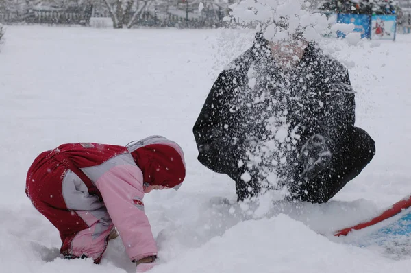 Estilo de vida de inverno. Pai e filha vestindo roupas quentes desfrutar de neve no parque — Fotografia de Stock