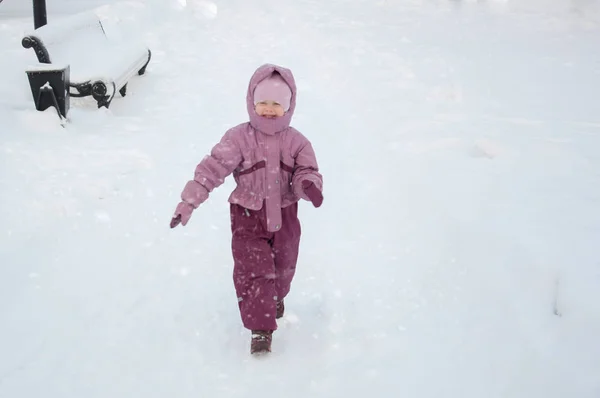 Inverno no parque. Uma menina usando roupas quentes andando pelo snowfalll no parque — Fotografia de Stock