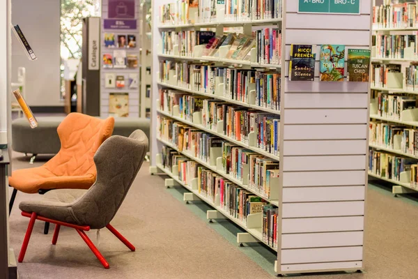 Sydney, Australia - 2019-07-19 In the local library. Chairs waiting for readers and bookshelfs full of books. Sutherland, NSW — Stock Photo, Image