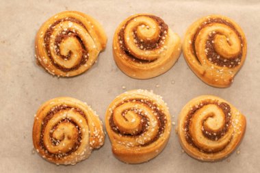 Taze pişmiş tarçınlı çörekler, parşömen kağıdıyla kaplı bir tepside.