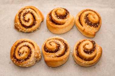 Taze pişmiş tarçınlı çörekler, parşömen kağıdıyla kaplı bir tepside.