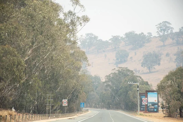 Canberra, Australien 2019-12-28 Australisk bushfire: rökdimma från skogsbränder över Canberra vägskylt. Ohälsosamma luftförhållanden. — Stockfoto