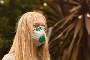 Avustralya çalı yangını: P2 N95 koruma maskesi takan sarışın kız çalıların dumanından nefes alan Pm2.5 parçacıklarının miktarını azaltmak için solunum maskesi.