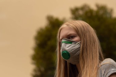 Avustralya çalı yangını: P2 N95 koruma maskesi takan sarışın kız çalıların dumanından nefes alan Pm2.5 parçacıklarının miktarını azaltmak için solunum maskesi.