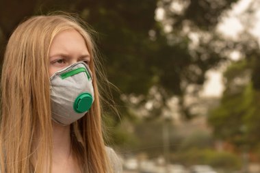 Avustralya çalı yangını: P2 N95 koruma maskesi takan sarışın kız çalıların dumanından nefes alan Pm2.5 parçacıklarının miktarını azaltmak için solunum maskesi.
