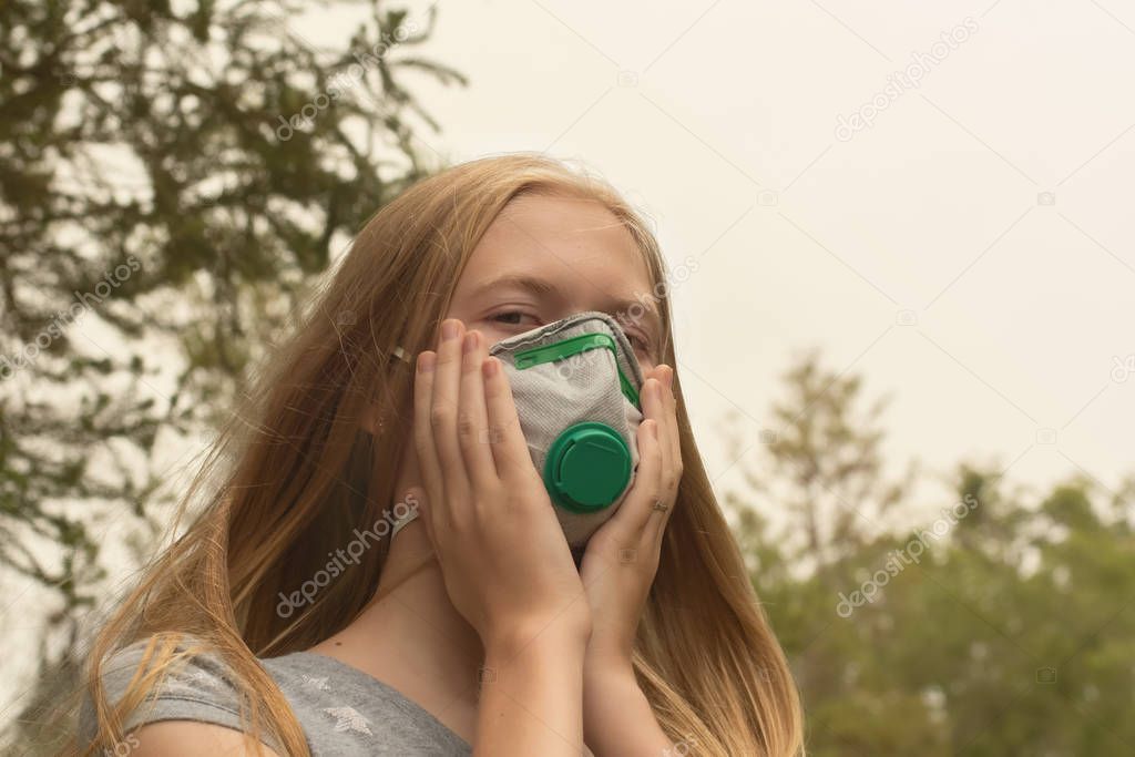 Australian bushfire: blond girl wearing P2 protection respiratory mask to reduce amount of breathing PM2.5 particles from bushfire smoke.