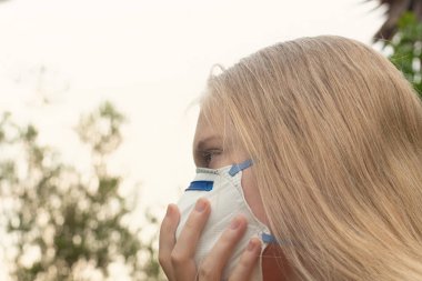 Avustralya çalı yangını: P2 N95 koruma maskesi takan sarışın kız çalıların dumanından nefes alan Pm2.5 parçacıklarının miktarını azaltmak için solunum maskesi.