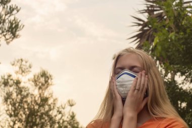 Avustralya çalı yangını: P2 N95 koruma maskesi takan sarışın kız çalıların dumanından nefes alan Pm2.5 parçacıklarının miktarını azaltmak için solunum maskesi.