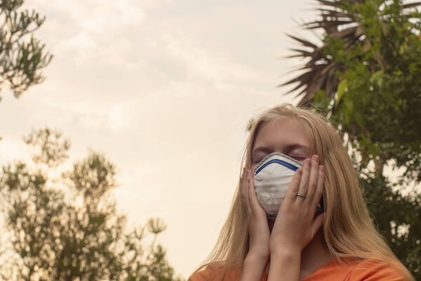 Australian bushfire: blond girl wearing P2 N95 protection respiratory mask to reduce amount of breathing PM2.5 particles from bushfire smoke.
