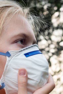 Solunum maskesi takan sarışın kız PM2.5 partiküllerini azaltmak için P2 N95 koruma maskesi takıyor