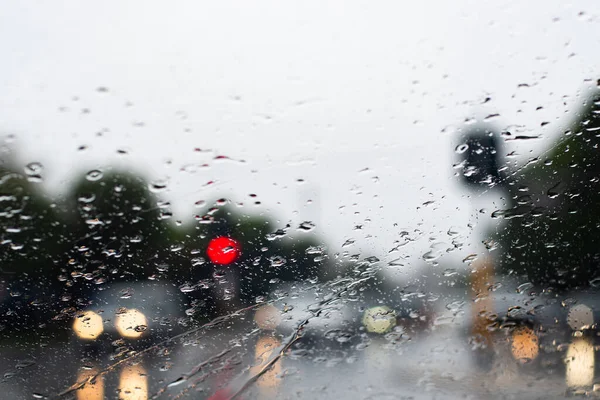 Проливной дождь через лобовое стекло. Машины с фарами едва видны на дороге. Селективный фокус — стоковое фото