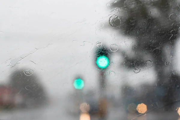 Heavy torrential rain hits the city. Traffic lights are barely seen through the windscreen. — Stock Photo, Image