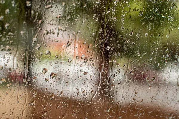 Проливной дождь на улице через окно с капельками дождя — стоковое фото