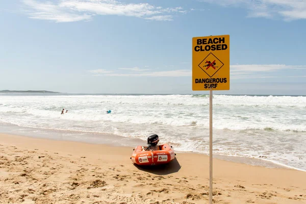 Cronulla, Ausztrália 2020-02-15 Beach closed sign and surf rescue boat at the beach in Sydney. A figyelmeztetés ellenére az emberek még mindig úsznak és szörföznek. — Stock Fotó
