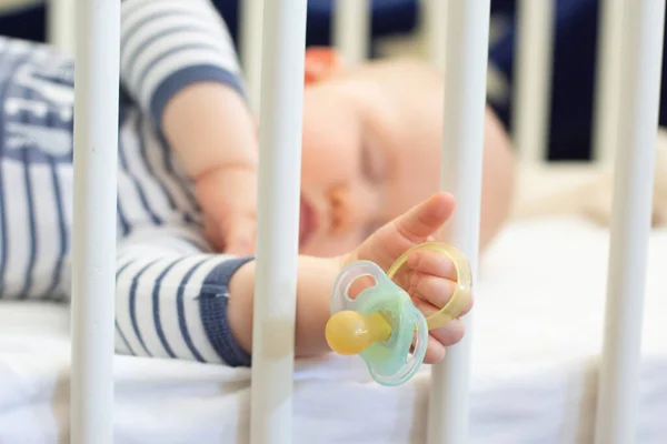 Immagine azzurrata del bambino che dorme tranquillamente e tiene in mano un manichino del ciuccio. Focus selettivo su un manichino — Foto Stock