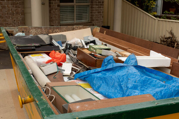 Sydney, Australia 2020-02-15 Skip bin full of household waste rubbish on the front yard. House clean up concept