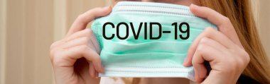 Virüslerin yayılmasını önlemek için tek kullanımlık yüz maskesi tutan bir kız. Coronavirus ve Covid-19 Kavramı