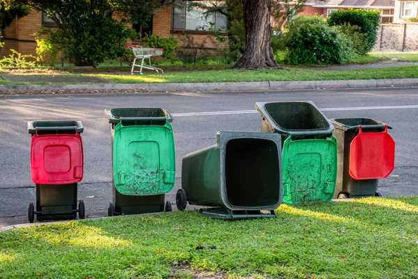Australian garbage wheelie bins staying and laying on a kurb side after council colleciton. Green lids are for green garden waste and red lids are for general household garbage