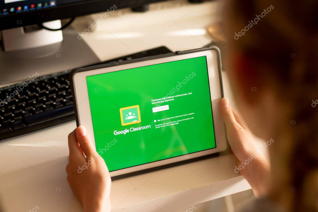 Sydney, Australia - 2020-04-06 Hands holding a tablet with Google Classroom application on screen. Coronavirus lockdown online education concept