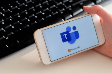 Sydney, Avustralya - 2020-04-15 Hands Microsoft Team ile birlikte akıllı telefonu tutuyor - takım çalışması merkezi ve grup sohbet uygulaması. Coronavirus çevrimiçi eğitim ve ev kavramından çalışma