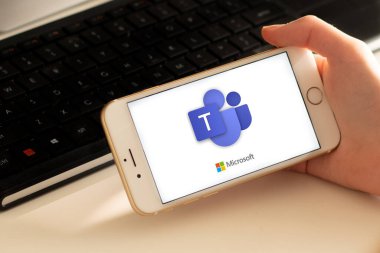 Sydney, Avustralya - 2020-04-15 Hands Microsoft Team ile birlikte akıllı telefonu tutuyor - takım çalışması merkezi ve grup sohbet uygulaması. Coronavirus çevrimiçi eğitim ve ev kavramından çalışma