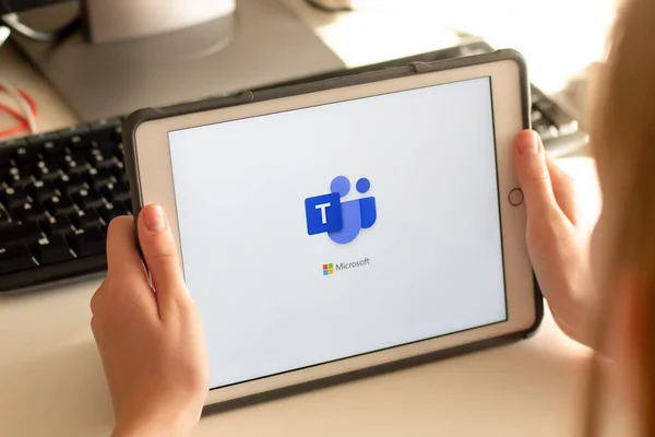 Sydney, Avustralya - 2020-04-15 Hands Microsoft Team ile bir tablet tutuyor - takım çalışması merkezi ve grup sohbet uygulaması. Coronavirus çevrimiçi eğitim ve ev kavramından çalışma