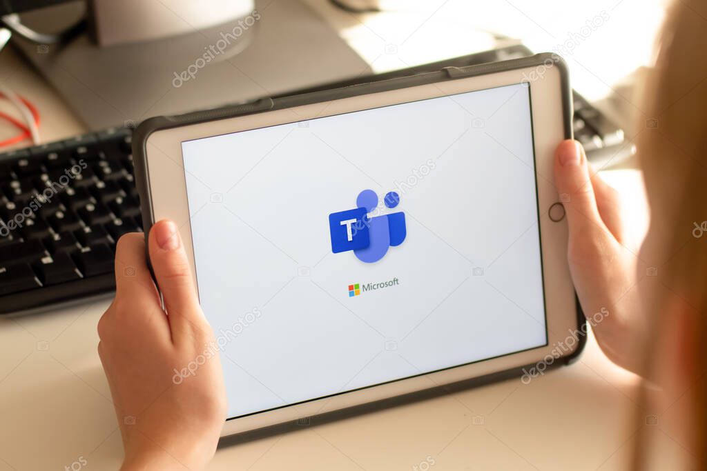 Sydney, Australia - 2020-04-15 Hands holding a tablet with Microsoft Team - teamwork hub and group chat platform app. Coronavirus lockdown online education and work from home concept