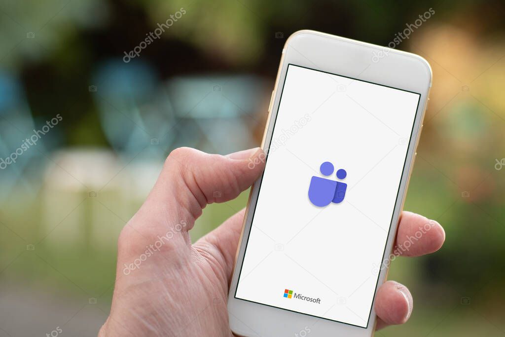 Sydney, Australia - 2020-04-15 Hands holding smartphone with Microsoft Team - teamwork hub and group chat platform app. Coronavirus lockdown online education and work from home concept