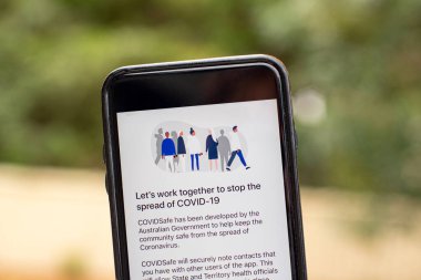 Sydney, Avustralya 2020-04-26 Hand CovidSafe uygulamalı bir telefon tutuyor. Virüsü durdurmak için birlikte çalışalım. Avustralya Hükümeti yeni COVID-19 izleme uygulamasını tanıttı