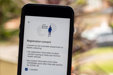 Sydney, Avustralya 2020-04-26 Hand CovidSafe uygulamalı bir telefon tutuyor. Ruhsat onaylama ekranı. Avustralya Hükümeti yeni COVID-19 izleme uygulamasını tanıttı