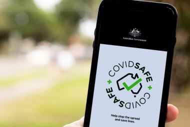 Sydney, Avustralya 2020-04-26 Hand CovidSafe uygulamalı siyah bir akıllı telefon tutuyor. Avustralya Hükümeti yeni COVID-19 izleme uygulamasını tanıttı