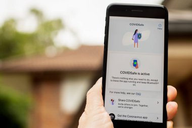Sydney, Avustralya 2020-04-26 Hand CovidSafe uygulamalı bir telefon tutuyor. Avustralya hükümeti koronavirüs salgınını durdurmak için yeni bir COVID-19 izleme uygulaması başlattı.
