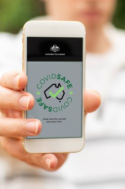 Sydney, Avustralya 2020-04-26 Hand CovidSafe uygulamalı siyah bir akıllı telefon tutuyor. Avustralya Hükümeti yeni COVID-19 izleme uygulamasını tanıttı