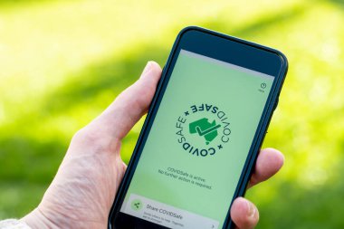 Sydney, Avustralya 2020-04-26 Hand CovidSafe uygulamalı beyaz bir akıllı telefon tutuyor. Avustralya Hükümeti yeni COVID-19 izleme uygulamasını tanıttı